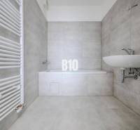 Bathroom with a bathtub and sink in a 3-room apartment, gray tiles, white radiator.