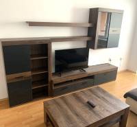 Living room with wooden furniture and wood-patterned flooring in a two-room apartment.