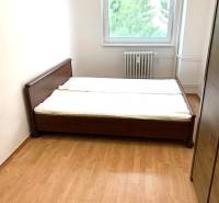 Bedroom in a 2-room apartment with wooden decor and a large window.