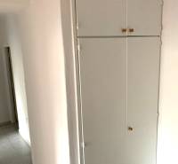 White built-in wardrobe in the hallway of a 2-room apartment with a tiled floor.