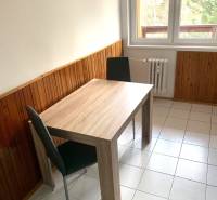 A kitchen in a 2-room apartment with wooden paneling and light tiles.