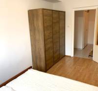 Bedroom with a bed, wardrobe, and wooden decor flooring in a 2-room apartment.