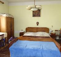 Bedroom in a family house with antique furniture, chandelier, painting, and wooden decor flooring.