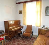 Living room with a piano, armchair, sofa, and a carpet with a red pattern in a family house.
