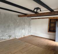Interior of a commercial space with a wood-patterned floor and prominent beams on the ceiling.