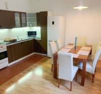 A kitchen in a 2-room apartment with a dining table, wooden cabinets, and a wooden decor floor.