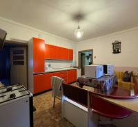 A kitchen in a family house with a red kitchen unit and a table with microwave ovens.
