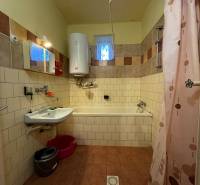 A bathroom in a family house with older sanitary fixtures, tiles, and a shower curtain.