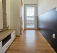 A hallway with a wooden decor floor in a family house, light and furniture by the wall.