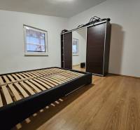A bedroom in a family house with a bed and a wardrobe, floor with wooden decor.