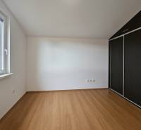 A room with a wooden decor floor in a family house, wardrobes, a window with a view.