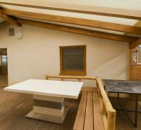 Terrace of a family house with a wooden decor roof and flooring, wooden structures, tables.