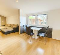 Interior of a family house with a wooden decor floor, a sofa set, and a dining table.