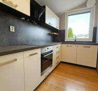 A kitchen in a family house with a wooden decor floor and a large window.