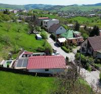 The hilly landscape of Banská Štiavnica with family houses on 8th May Street surrounded by greenery.