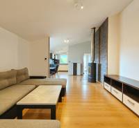 Living room in a family house with a comfortable sofa, a stove, and a wooden-patterned floor.
