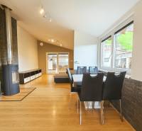 Interior of a family house with a wooden decor floor, a tiled stove, and a dining table.