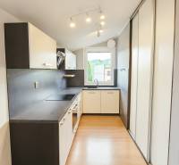 A kitchen in a family house with a wooden decor floor and modern lighting.
