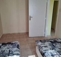 A room with ceramic tiles, a bed with a print, and white doors in a studio apartment.