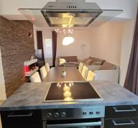 A kitchen in a 3-room apartment with a dining table, brick cladding, and a wooden decor floor.