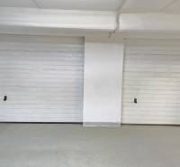 Garage doors in an enclosed space, white walls, safety markings.