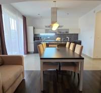 A spacious kitchen with a dining area and a wooden decor floor in a 3-room apartment.