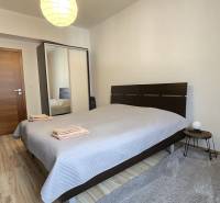 A bedroom in a 3-room apartment with a wooden decor floor, a bed, and a lamp.