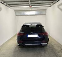A garage with a Mercedes-Benz C223d with a concrete floor and white walls.