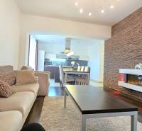Living room in a 3-room apartment with a wooden decor floor, decorative wall, and fireplace.