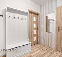 Entrance hall in a 3-room apartment with coat racks, a mirror, and a wooden decor floor.