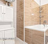 A bathroom with a bathtub, white cabinets, and tiles in a 3-room apartment.