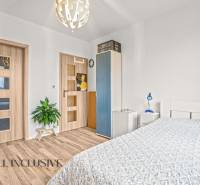 A bedroom in a three-room apartment with a wooden decor floor and simple furnishings.