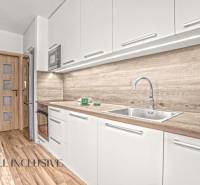 A kitchen with light cabinets, wood-patterned flooring, and a sink in a 3-room apartment.