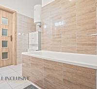 Bathroom in a 3-room apartment with a bathtub, beige tiles, and wooden doors.