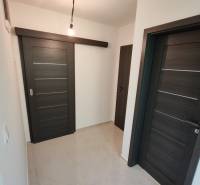 A hallway in a 3-room apartment with dark sliding doors and a light floor.