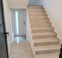 A hallway with a staircase and white walls in a 3-room apartment.
