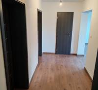 The interior of a three-room apartment with a wood-patterned floor and neutral walls.