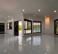 The interior of the villa with white floors and large windows overlooking the garden.
