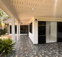 Pattaya villa with a terrace, glass doors, plants, and mosaic paving in the garden.