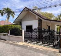 A villa in Pattaya with a decorative metal gate, surrounded by greenery and palm trees.