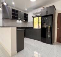 A kitchen in a villa with dark cabinets, white tiles, and a spacious floor.