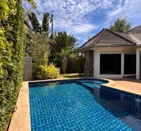 A villa in Pattaya with a pool surrounded by greenery and a blue sky.
