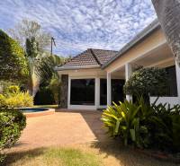 A villa in Pattaya surrounded by a landscaped garden with a paved terrace.