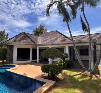 A villa in Pattaya with a pool surrounded by palm trees and greenery.