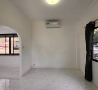 The interior of a villa with a white floor and an arched passage in the wall.