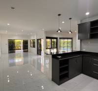 A kitchen in a villa with white walls, tiles, and dark furniture.