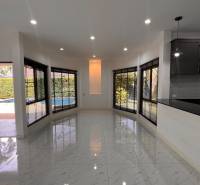Interior of a villa with a garden view, large windows, and tiled flooring.