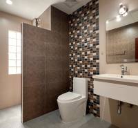 A bathroom in a villa with ceramic tiles and a modern mirror above the sink.