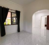 The interior of a villa with a tiled floor, arched doors, and curtains on the window.