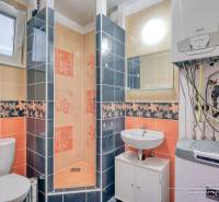 A bathroom in a family house with colorful tiles, a sink, a toilet, and a boiler.